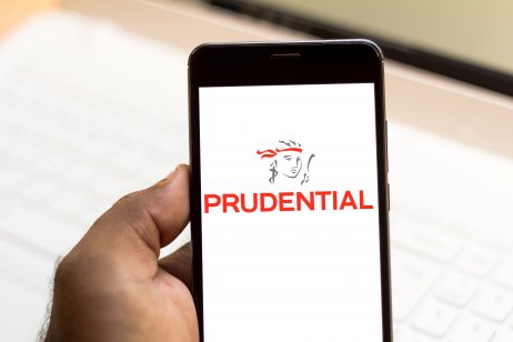 A hand holding a mobile phone with a Prudential logo on it