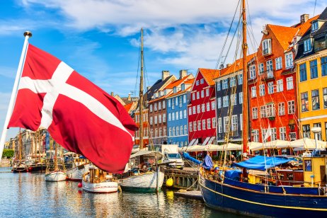 The famous view of Copenhagen. The famous old port of Nyhavn in the center of Copenhagen, Denmark, on a sunny summer day with the flag of Denmark in the foreground.