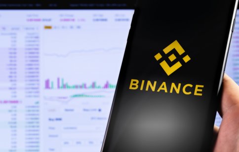 Binance logo on a smartphone in front of a computer screen