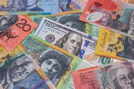 A hundred US dollar bill from and colorful Australian dollars banknotes, symbolizing the AUD/USD exchange rate