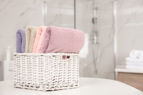 Basket with color towels on white table in bathroom.