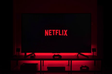 Big Netflix logo on a TV in a dark room with red lights in the background — (Photo: WeDesing / Shutterstock.com)