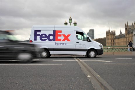 FedEx stock forecast: Set to deliver success in 2023? London, UK / March, 2020 / A FedEx courier van parked up in Westminster bridge, with an abstract London taxi driving by. Logo clearly in focus, and you can see the House's of Parliament in view.