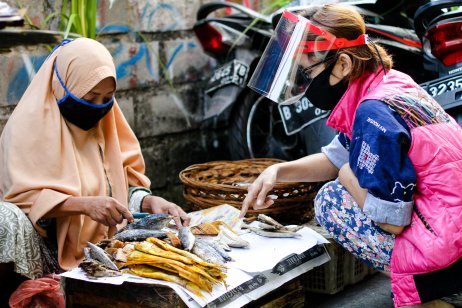 A Western tourist inspects dried fish in a market in Jakarta, Indonesia