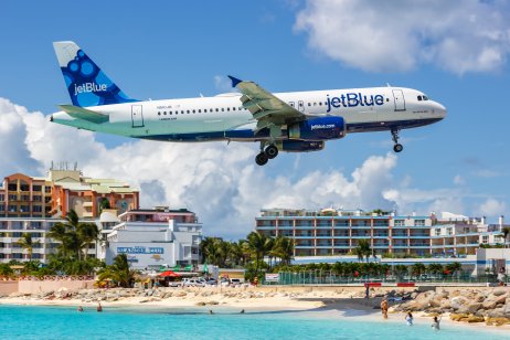 JetBlue airplane flying over a beach