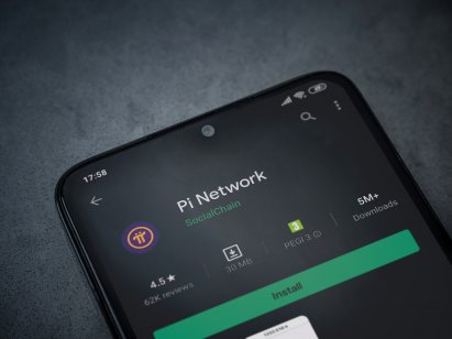 Pi Network app play store page on the display of a black mobile smartphone on dark marble stone background. Top view flat lay with copy space.