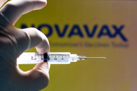 A medical syringe in front of the Novavax company logo