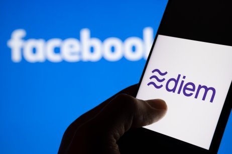 A hand holding phone with diem logo on a display against blue backround with Facebook logo.
