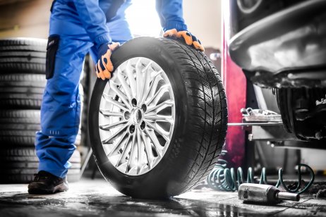 Car mechanic working in a garage and changing wheel alloy tire
