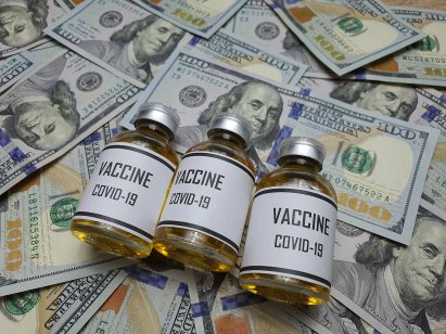 Three vials of Covid-19 vaccine rest on hundred dollar bills