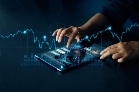 A man's hands work a computer tablet, which is overlaid with a trading chart