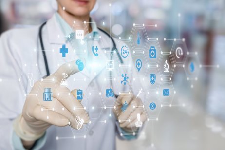 Doctor working on a virtual screen behind the structure of medical icons on a blurred background.