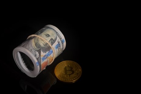 Money banknote and golden bitcoin over black background.