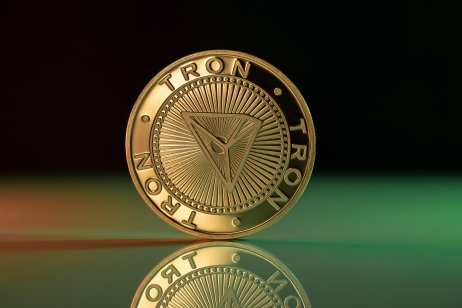 Tron price prediction. Tron TRX cryptocurrency physical coin placed on reflective surface and lit with green and red lights