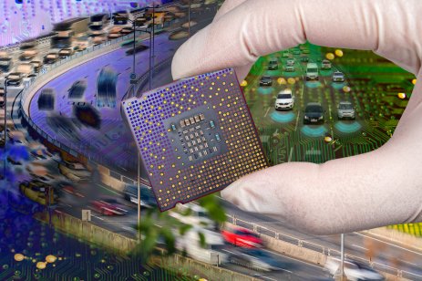 A hand holding a CPU chip set over a computer circuit board with fast-moving cars