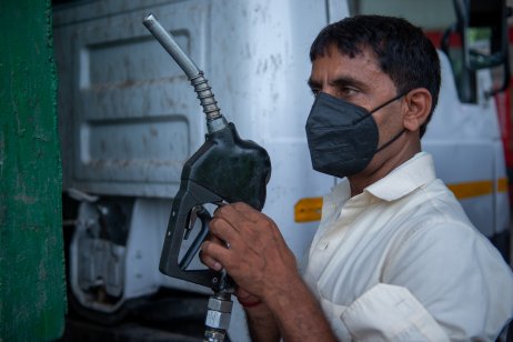 A man in mask holding oil nozzle at a petrol pump in New Delhi, India 
