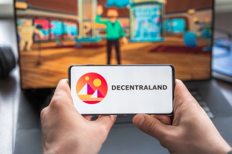 Russia Moscow 30.05.2021.Logo,screenshot of blockchain nft ethereum cryptocurrency game Decentraland in laptop,mobile phone.Man playing with crypto coins,token MANA.Earning digital money.Lands,heroes.