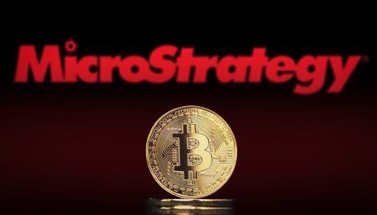 Bitcoin BTC representation coin with MicroStrategy logo in background.