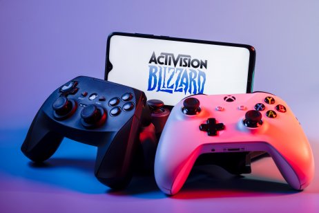 A smartphone with the Activision Blizzard logo on the screen on the pile of the gamepads