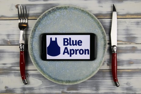 Closeup of mobile phone screen with logo lettering of blue apron online foods delivery service on dish (focus on center of phone screen)