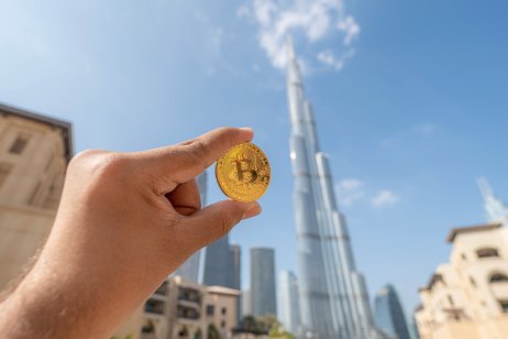 A hand holding bitcoin (BTC) coin in downtown Dubai.