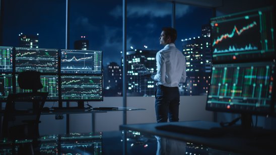 A financial trader surrounded by multiple screens