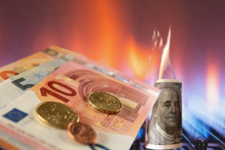 An image showing Euro banknotes lie next to a burning gas burner and a burning dollar, concept of energy crisis