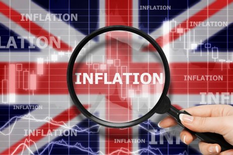 Magnifying glass focused on the word inflation on UK flag background.