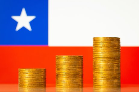 Stacks of golden coins with flag of Chile on the background. 
