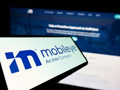 Smartphone with logo of Israeli autonomous driving company Mobileye on screen in front of business website. Focus on center-left of phone display. 