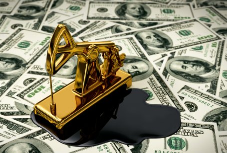 Golden pumpjack and spilled oil on US dollar banknotes