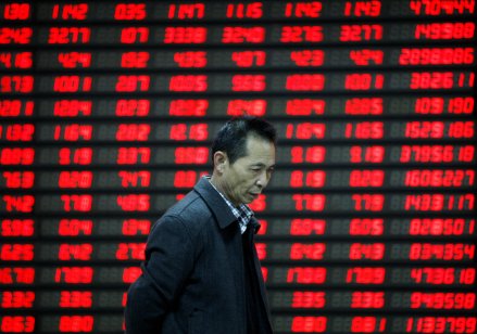 Person walks past a stock screener board in China