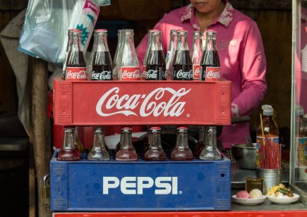 Man selling Coke and Pepsi in red and blue crates