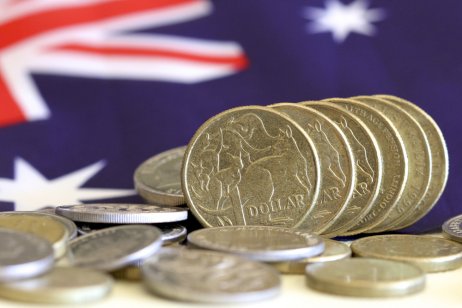 Australian dollar coins and Australian flag in the background 