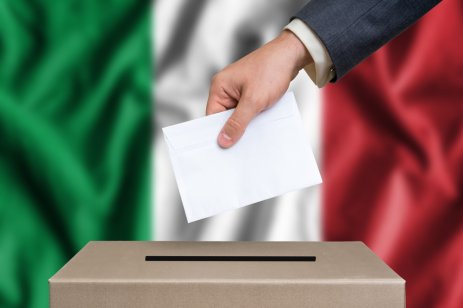 Concept of italian elections. An image shows The hand of man putting his vote in the ballot box with the italian flag on the background
