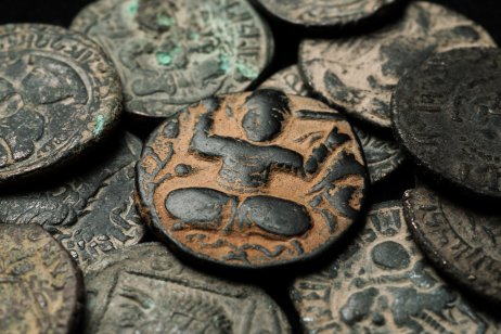 Ancient islamic copper coin in pile of other coins 