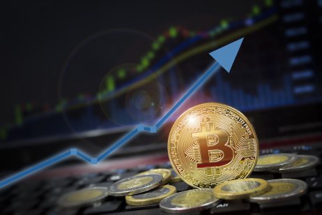 Bitcoin currency against graph with arrow showing upward trend