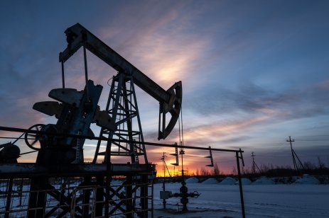 A jack pump in an oil field during sunset