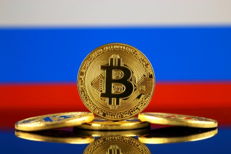 Coin with bitcoin (BTC) logo against flag with Russian background.