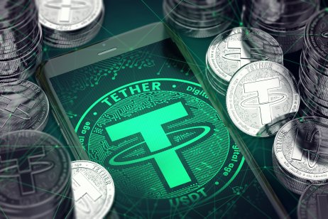 A smartphone with a green Tether symbol on the screen among the Tether coins.