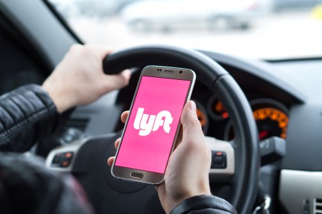 Lyft stock forecast: Will ride-hailing app recover from plunge? Lyft driver holding smartphone in car. Lyft is an American company offering transportation services online. Illustrative editorial.