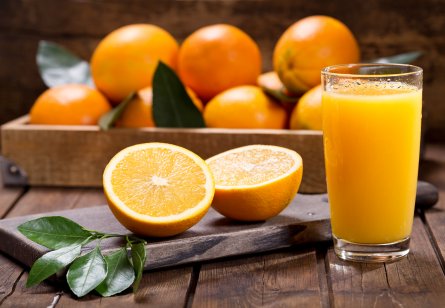 a glass of fresh orange juice with fresh fruit on a wooden table