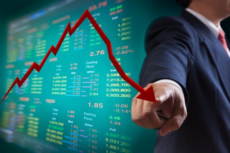 Man with a stocks chart and arrow pointing down Image of businessman holding a red down-pointing arrow on a stocks chart