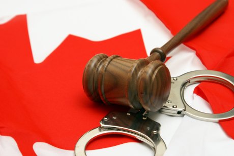 A gavel and handcuffs on a Canadian flag