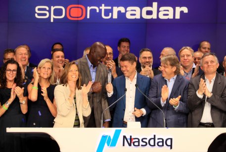 Photo of Sportradar CEO Carsten Koerl ringing the Nasdaq opening bell on 14 September accompanies by employees along with investors Michael Jordan and Todd Boehly