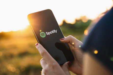 Spotify playing on phone in woman's hand with sunset 