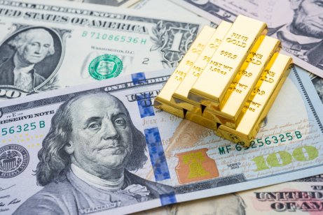 Gold bars on US dollar bill banknotes background.