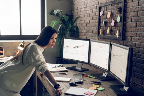 Female trader at a desk with market screens
