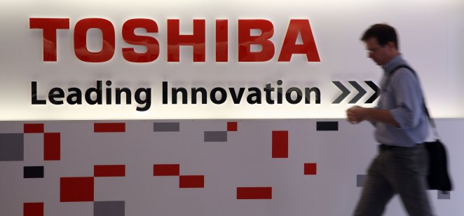 A man walking past the Toshiba logo