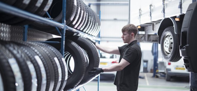 Apprentice engineer selecting tyres in car service centre - stock photo